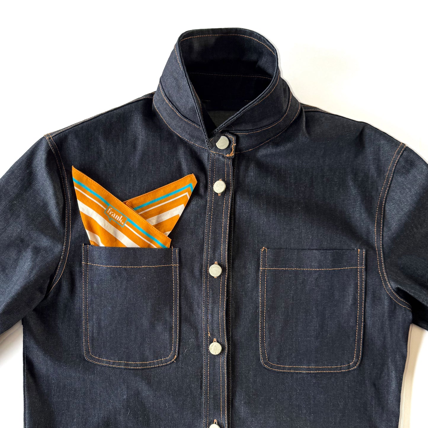 Denim jacket with a gold and white striped handkerchief in the pocket on a white background