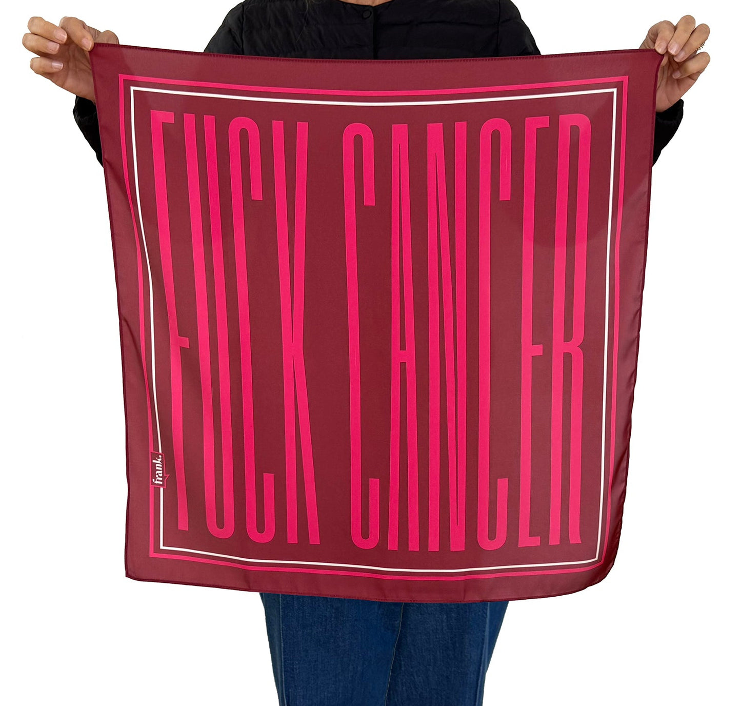 Person holding a silky burgundy scarf with 'FUCK CANCER' printed in pink.