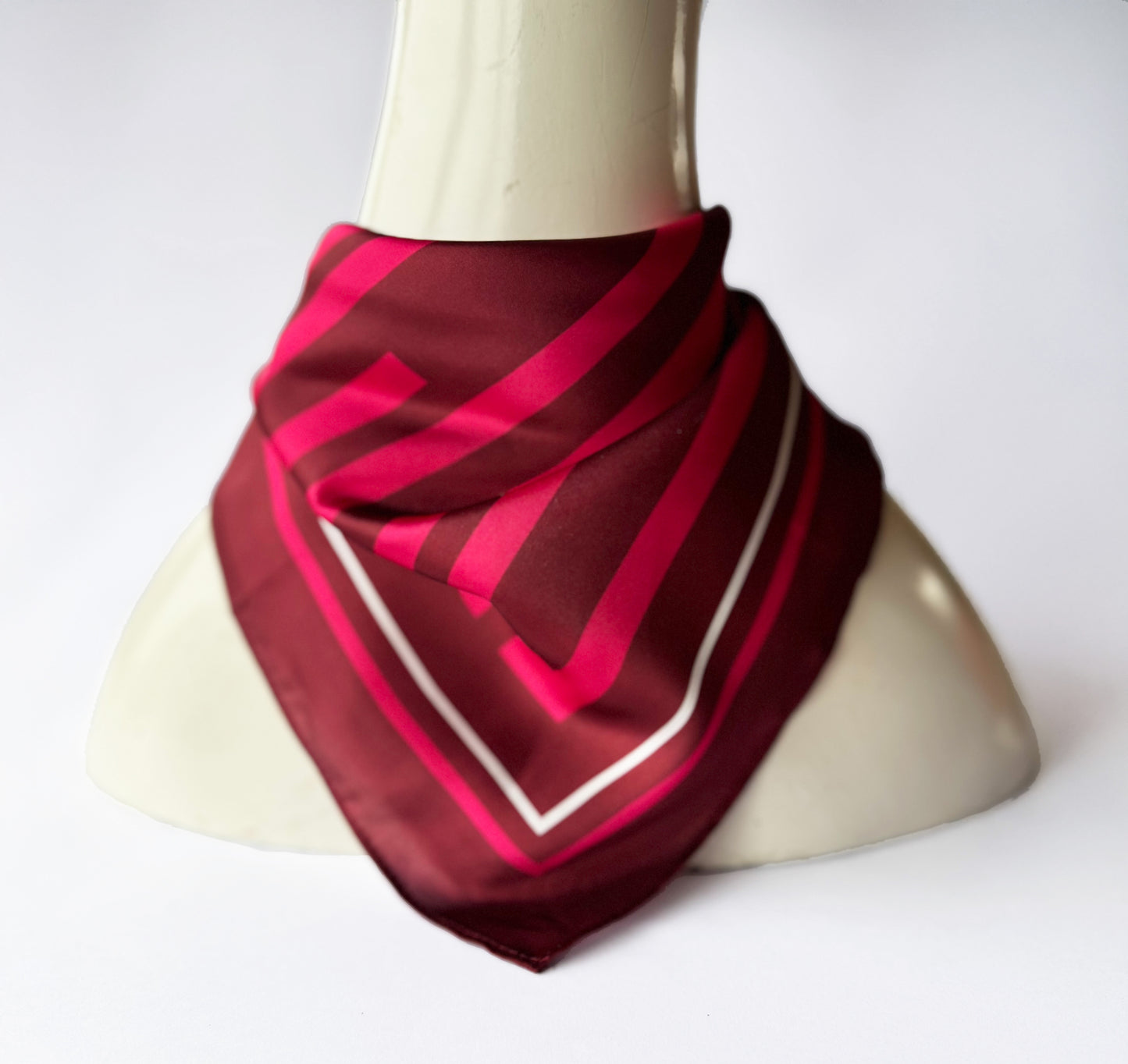 Burgundy and pink striped scarf on a mannequin against a white background