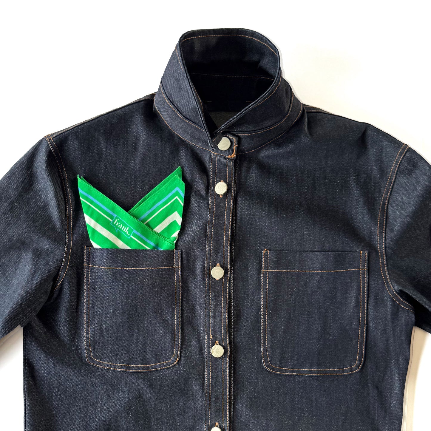 Denim jacket with a bright green and white striped handkerchief in the pocket on a white background