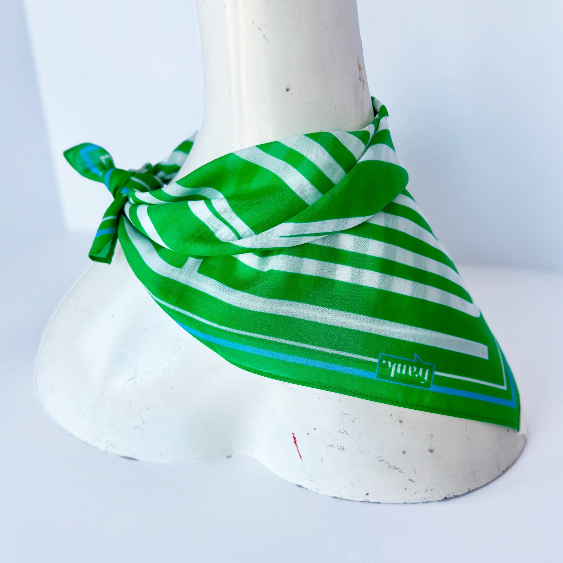 Green and white striped handkerchief on a white mannequin with a plain background