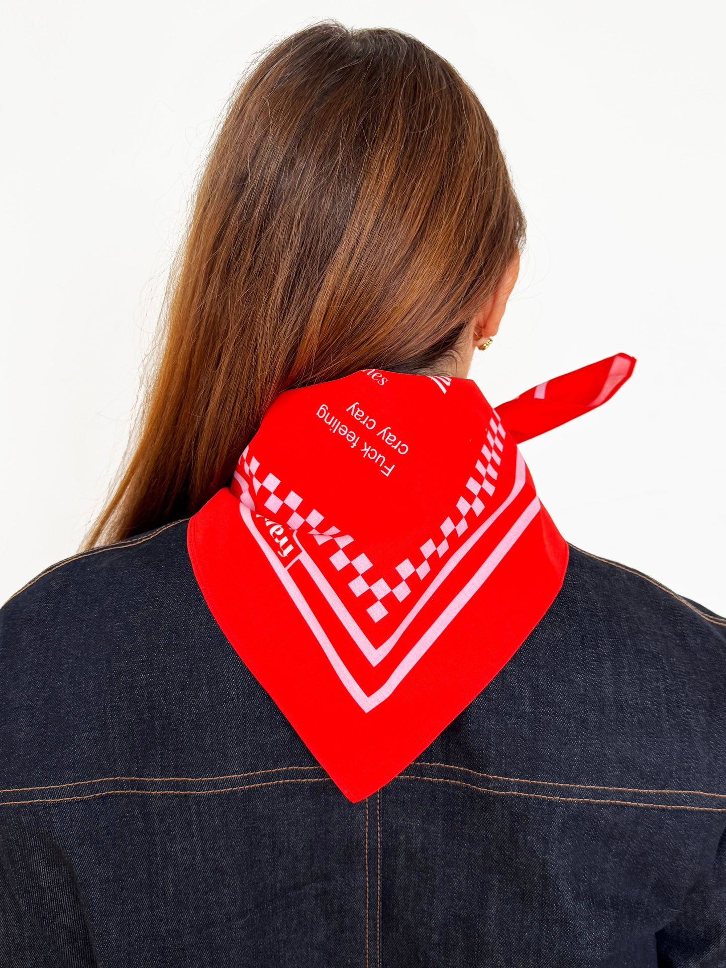 Backview of person wearing a deep orange bandana with white patterns on a plain background