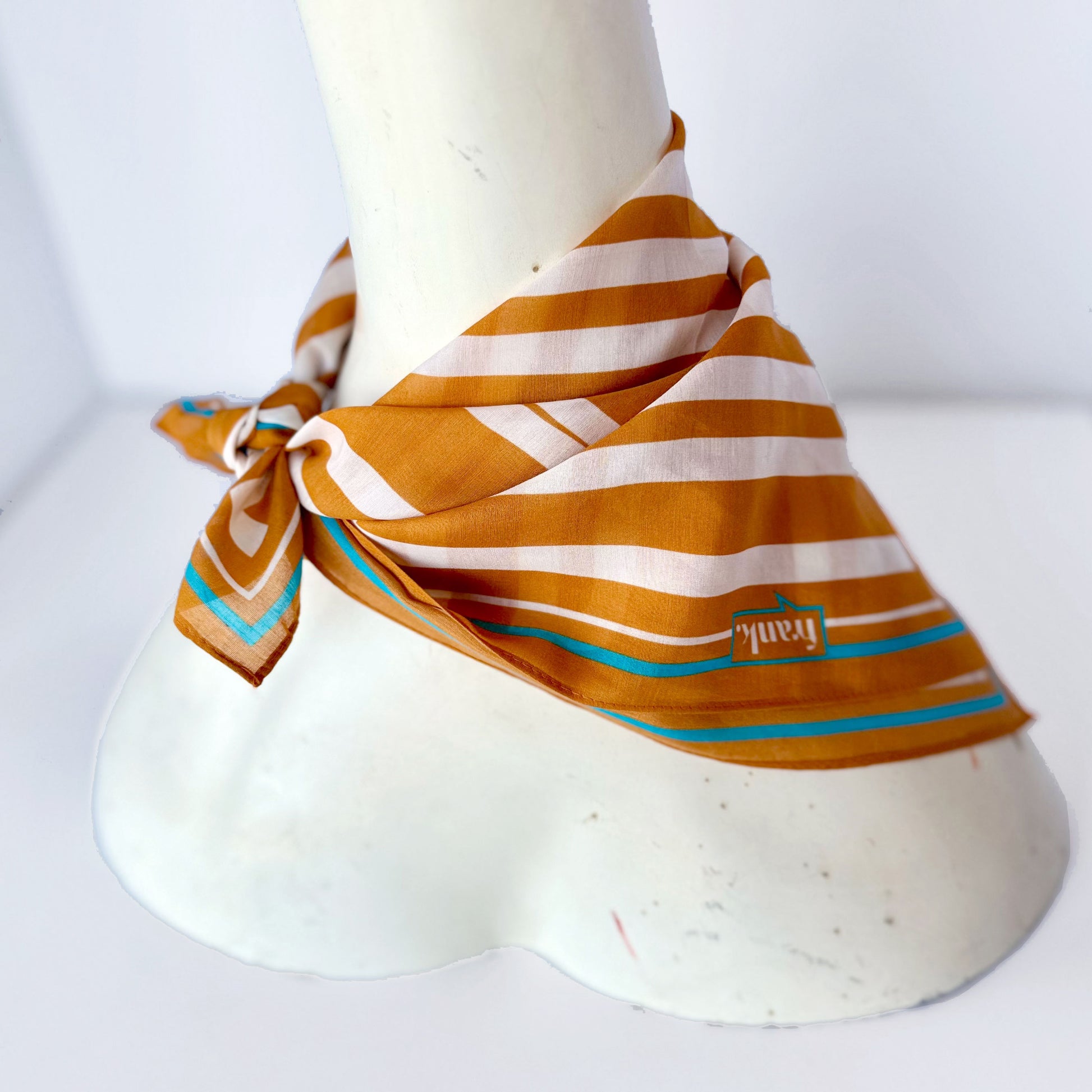Striped gold and white handkerchief with turquoise accents on a mannequin bust against a white background