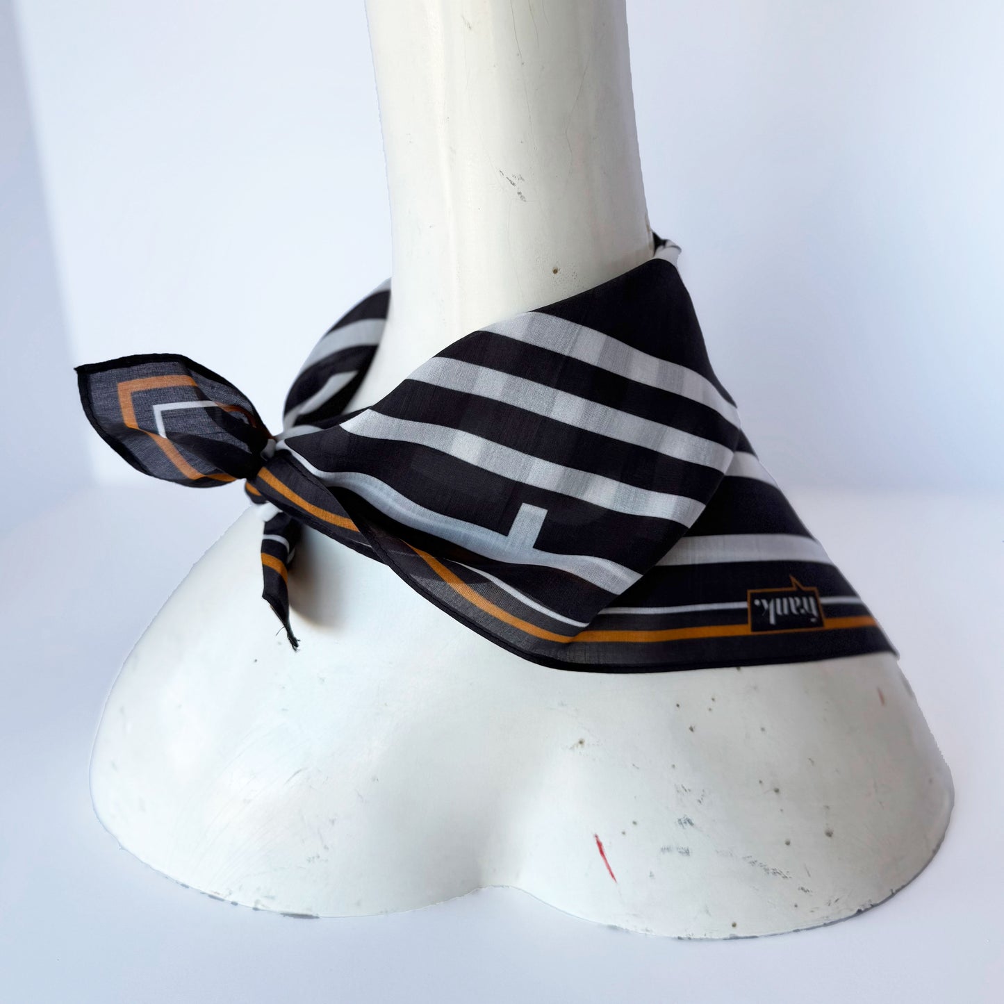 Black and white striped handkerchief with gold accents on a mannequin against a white background