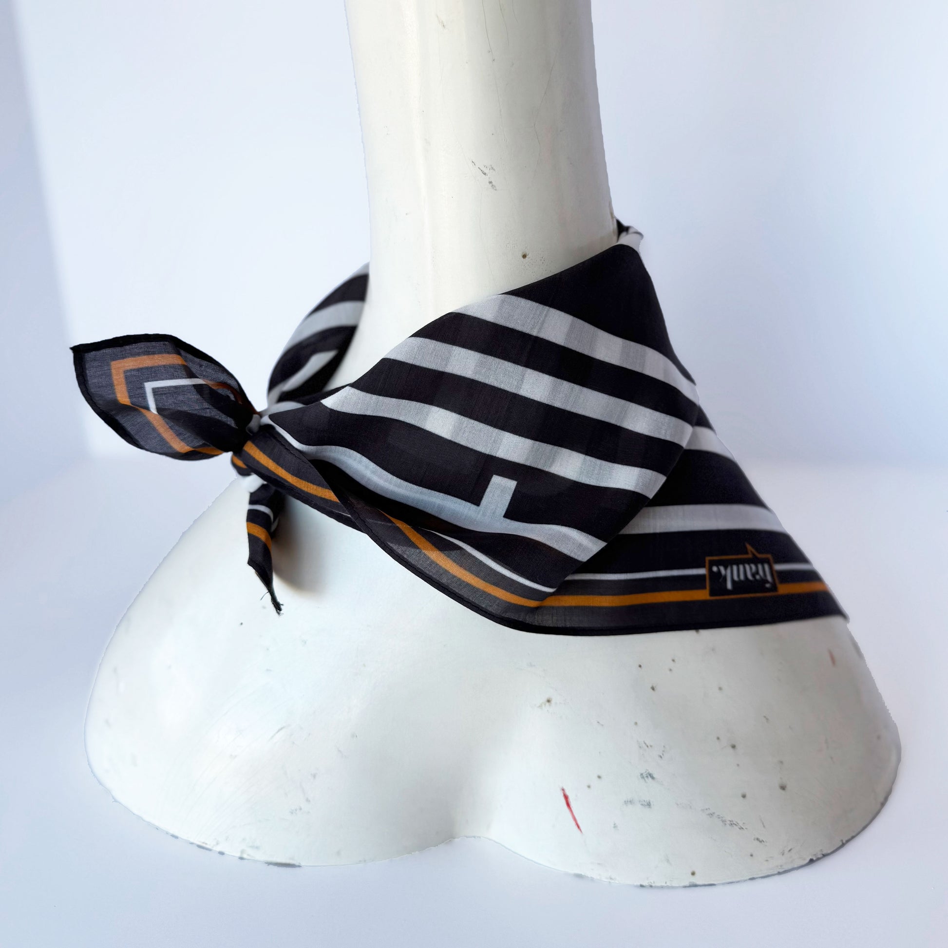 Black and white striped handkerchief with gold accents on a mannequin against a white background