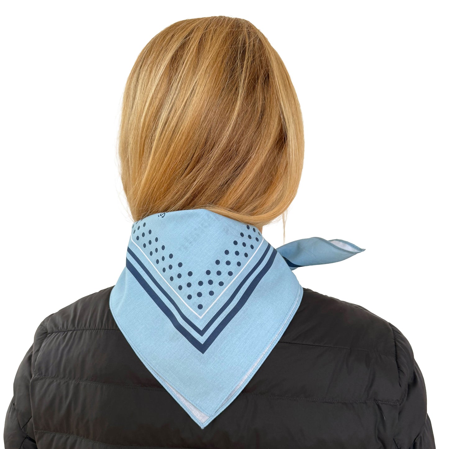 Person wearing a light blue scarf with dark polka dots over a black jacket on a white background