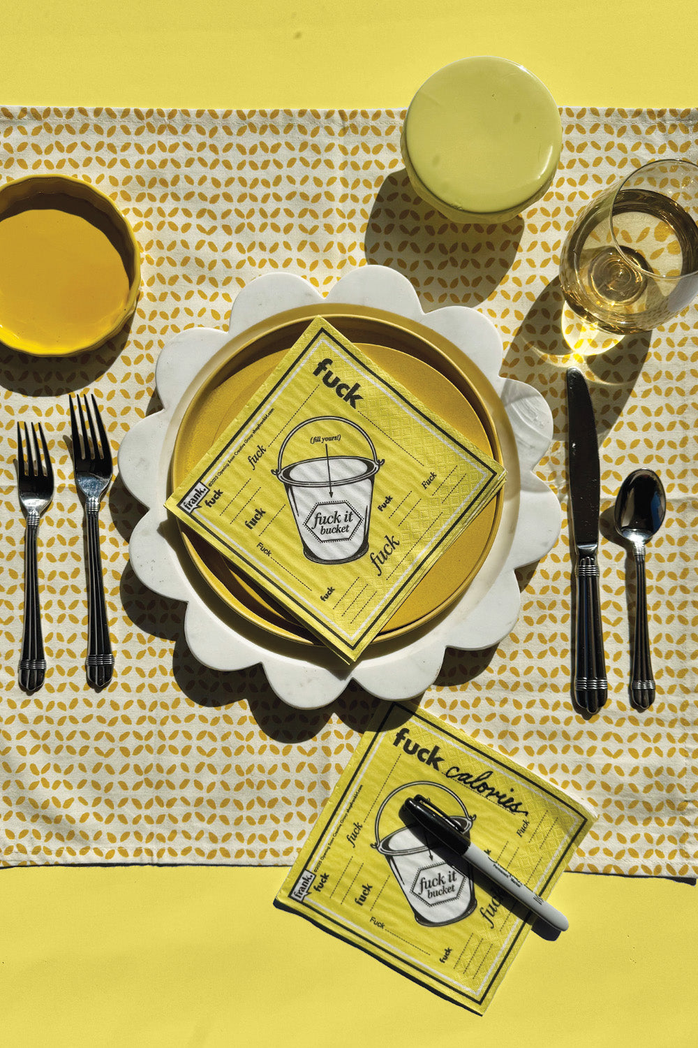 Yellow and white table setting with a decorative napkin featuring text and graphics.